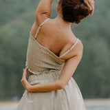 Woman wearing smocked beige linen tube top with spaghetti straps and short.