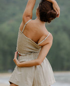 Woman wearing smocked beige linen tube top with spaghetti straps and short.