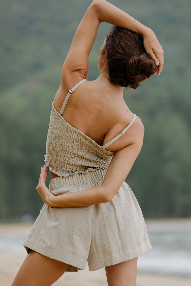 Woman wearing smocked beige linen tube top with spaghetti straps and short.