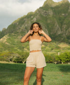 Woman wearing smocked beige linen tube top with spaghetti straps and short.