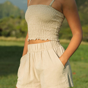 Woman wearing smocked beige linen tube top with spaghetti straps and short.