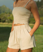 Woman wearing smocked beige linen tube top with spaghetti straps and short.