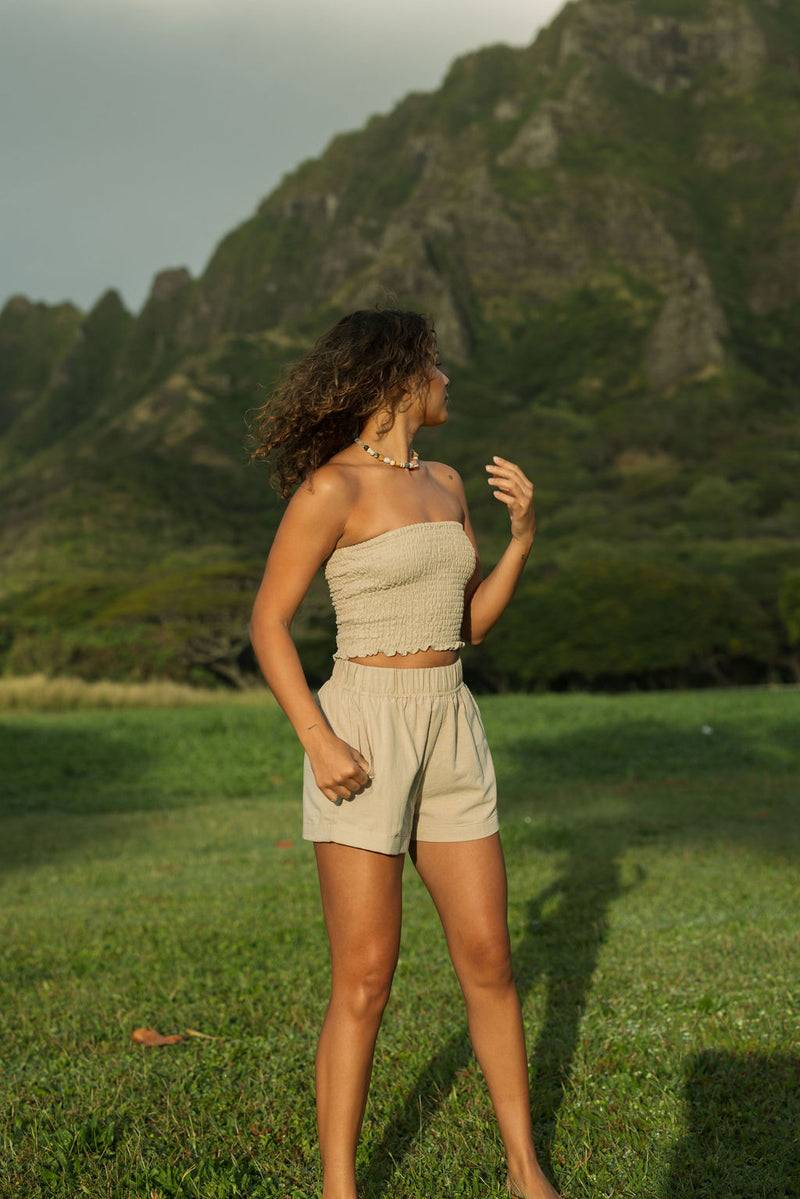 Woman wearing smocked beige linen tube top with short.