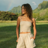 Woman wearing smocked beige linen tube top with spaghetti straps and short.