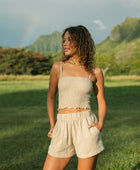 Woman wearing smocked beige linen tube top with spaghetti straps and short.