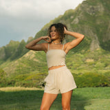 Woman wearing smocked beige linen tube top with spaghetti straps and short.