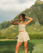 Woman wearing smocked beige linen tube top with spaghetti straps and short.