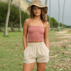 Woman wearing rose linen smocked tube top with spaghetti straps.