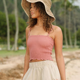 Woman wearing rose linen smocked tube top with spaghetti straps.
