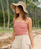 Woman wearing rose linen smocked tube top with spaghetti straps.