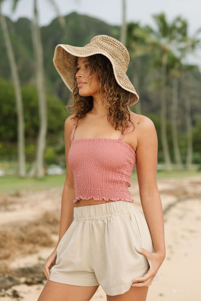 Woman wearing rose linen smocked tube top with spaghetti straps.