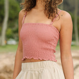 Woman wearing rose linen smocked tube top with spaghetti straps.