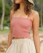 Woman wearing rose linen smocked tube top with spaghetti straps.