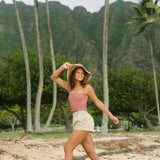 Woman wearing rose linen smocked tube top with spaghetti straps.