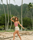 Woman wearing rose linen smocked tube top with spaghetti straps.