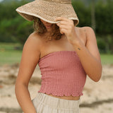 Woman wearing rose linen smocked tube top.