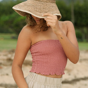 Woman wearing rose linen smocked tube top.