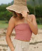 Woman wearing rose linen smocked tube top.