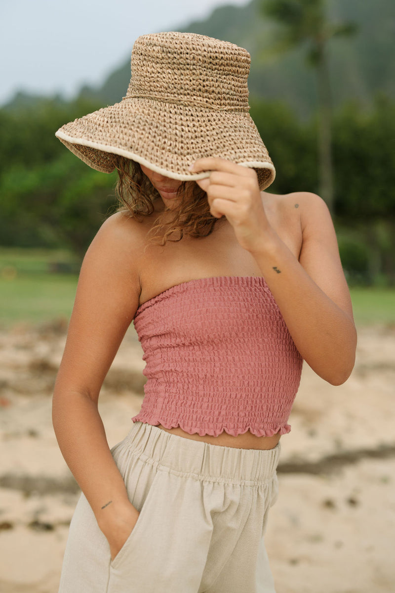 Woman wearing rose linen smocked tube top.