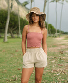 Woman wearing rose linen smocked tube top with spaghetti straps.