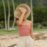 Woman wearing rose linen smocked tube top.