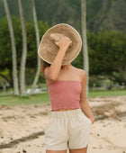 Woman wearing rose linen smocked tube top.