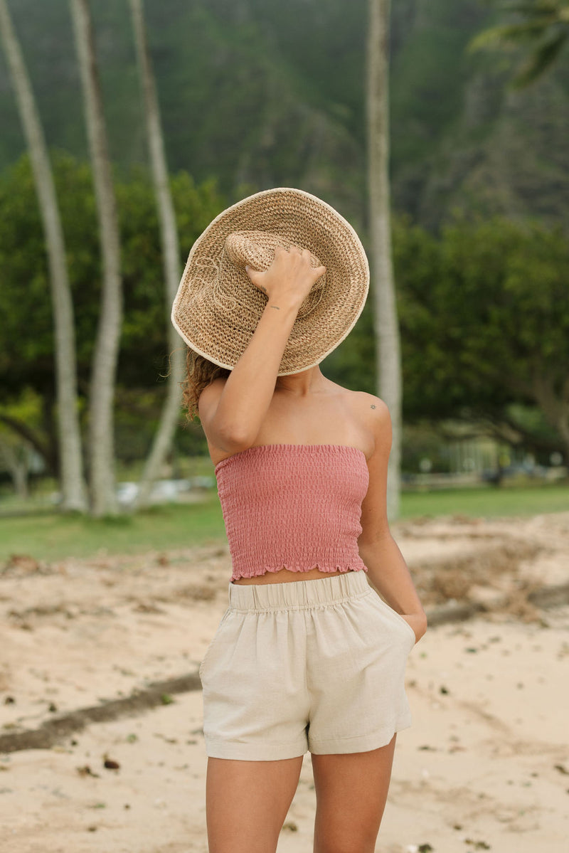 Woman wearing rose linen smocked tube top.