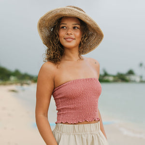 Woman wearing rose linen smocked tube top.