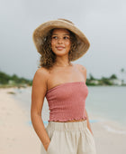 Woman wearing rose linen smocked tube top.