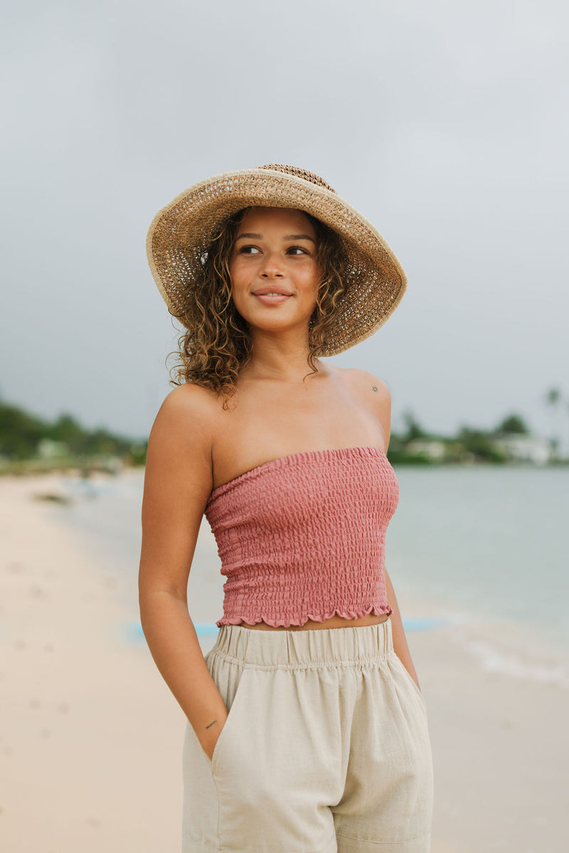 Woman wearing rose linen smocked tube top.