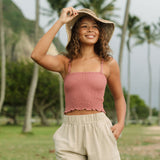 Woman wearing rose linen smocked tube top with spaghetti straps.