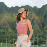 Woman wearing rose linen smocked tube top with spaghetti straps.