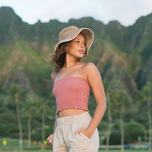 Woman wearing rose linen smocked tube top with spaghetti straps.