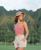 Woman wearing rose linen smocked tube top with spaghetti straps.