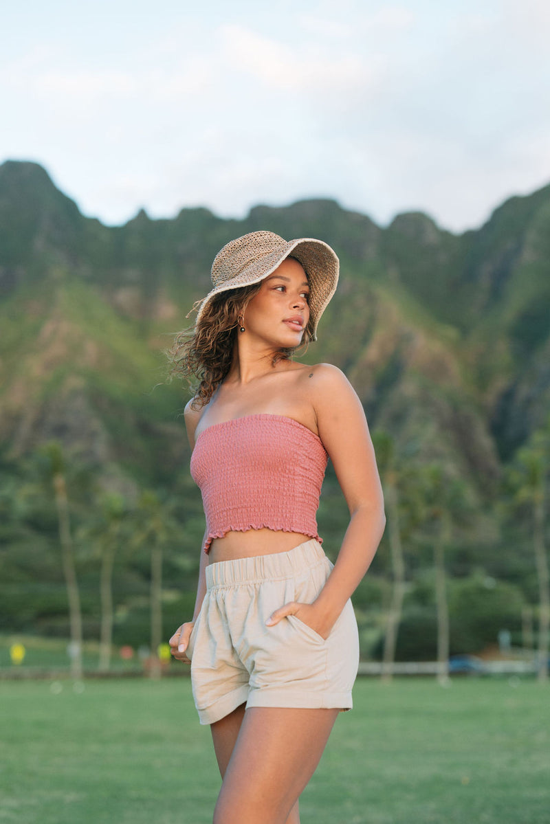 Woman wearing rose linen smocked tube top with spaghetti straps.