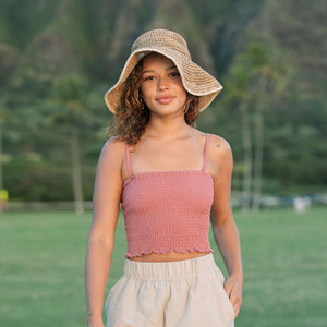 Woman wearing rose linen smocked tube top with spaghetti straps.