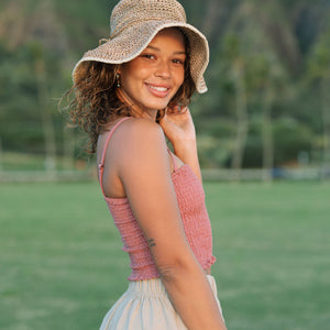 Woman wearing rose linen smocked tube top with spaghetti straps.