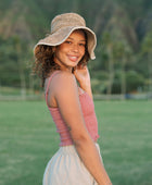 Woman wearing rose linen smocked tube top with spaghetti straps.