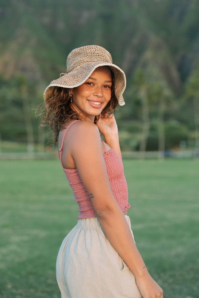 Woman wearing rose linen smocked tube top with spaghetti straps.