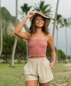 Woman wearing rose linen smocked tube top with spaghetti straps.