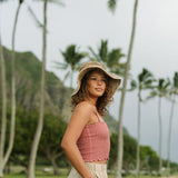Woman wearing rose linen smocked tube top with spaghetti straps.