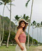 Woman wearing rose linen smocked tube top with spaghetti straps.