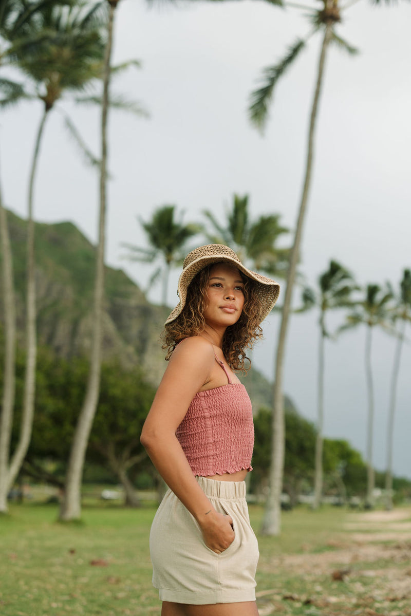 Woman wearing rose linen smocked tube top with spaghetti straps.