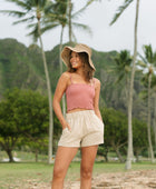 Woman wearing rose linen smocked tube top with spaghetti straps.