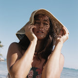 woman with brown hair wearing a teal bandeau top with removable straps with shell and pua print