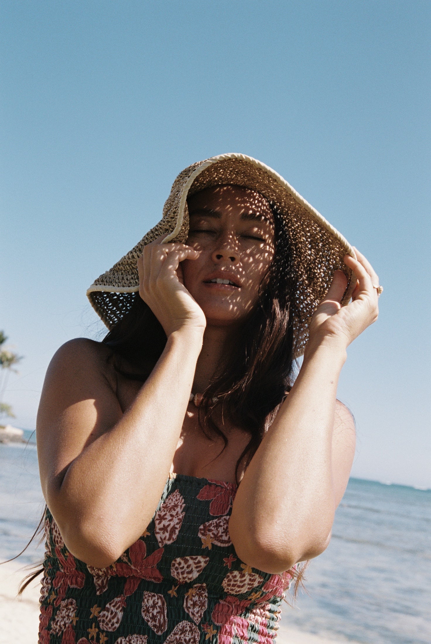 woman with brown hair wearing a teal bandeau top with removable straps with shell and pua print