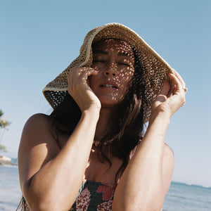woman with brown hair wearing a teal bandeau top with removable straps with shell and pua print