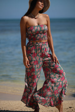 woman with brown hair wearing a teal elastic waist pant with open/slit legs in a shell and pua print