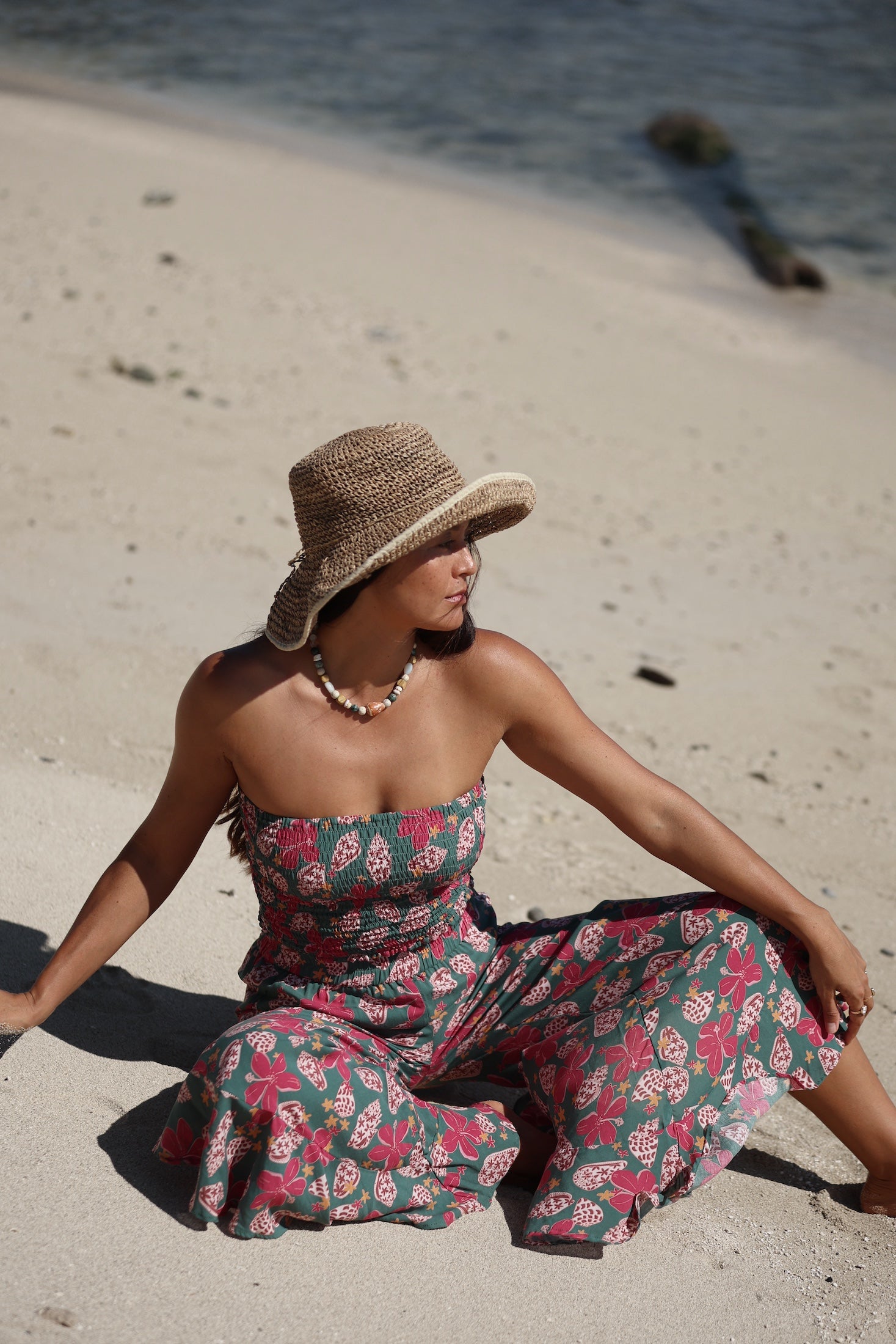 woman with brown hair wearing a teal bandeau top with removable straps with shell and pua print