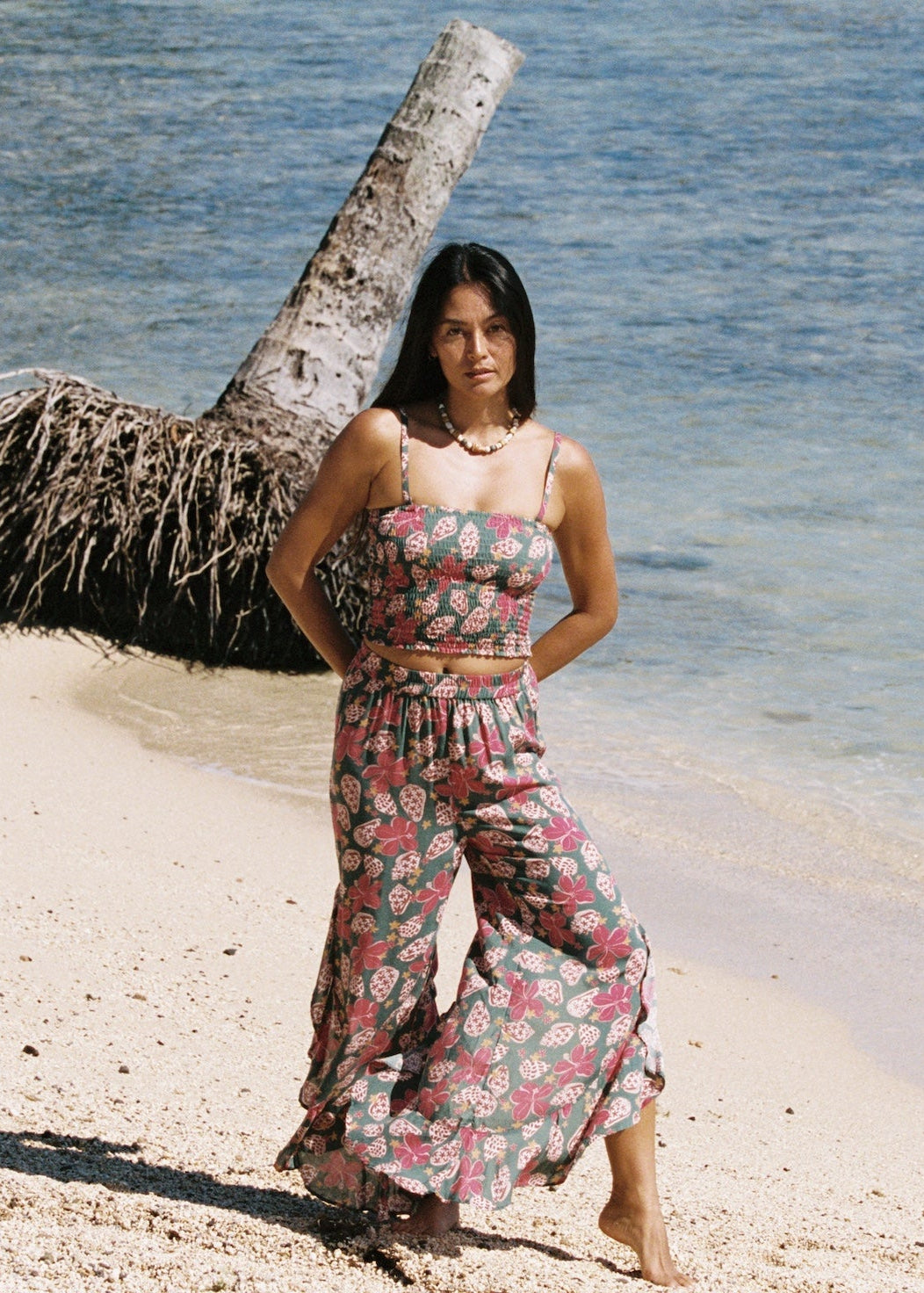 woman with brown hair wearing a teal elastic waist pant with open/slit legs in a shell and pua print